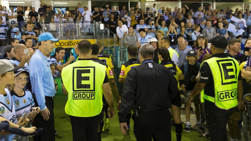 Security guards escort referees from the ground at Cronulla