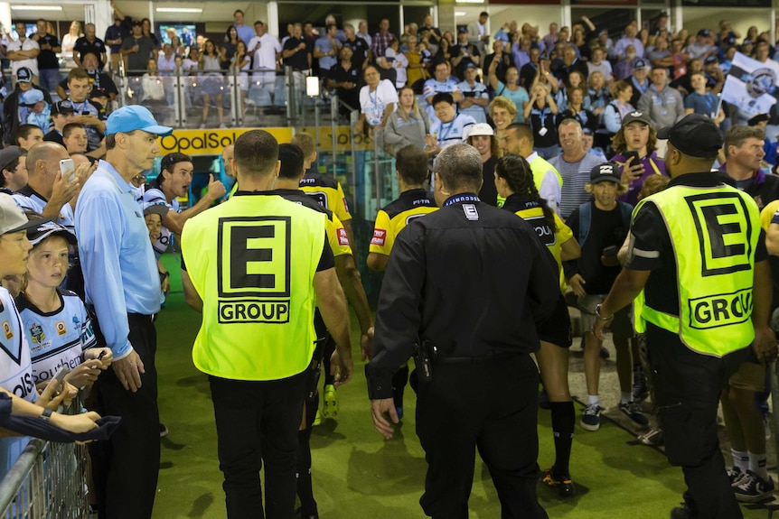 Security guards escort referees from the ground at Cronulla