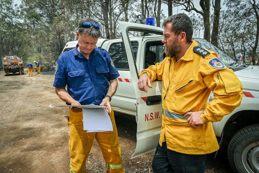 A man in a fire outfit discussing fire tactics with a another