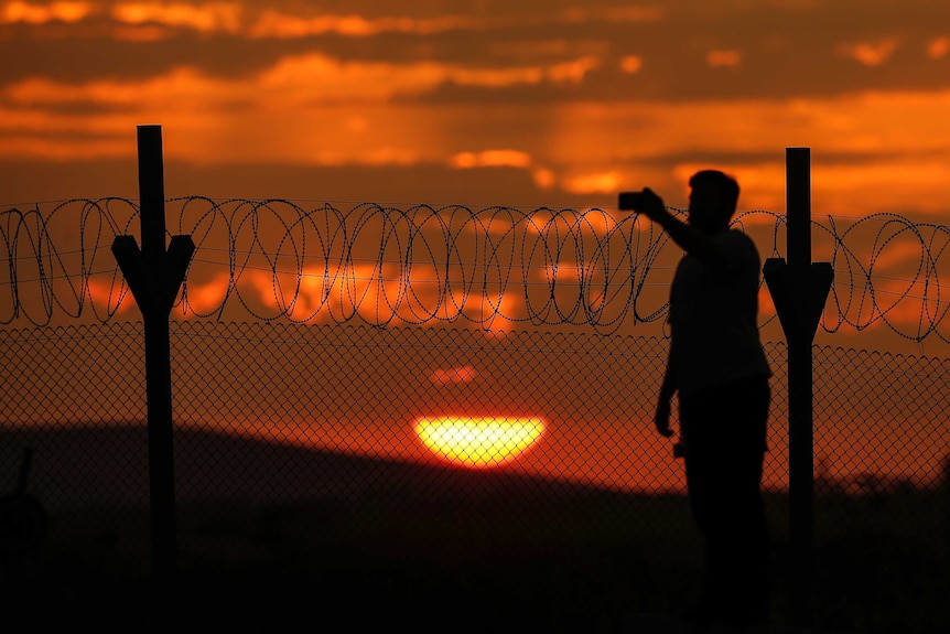 An orange sun sets behind the wire border fence on the Syria-Turkish border at Gaziantep.