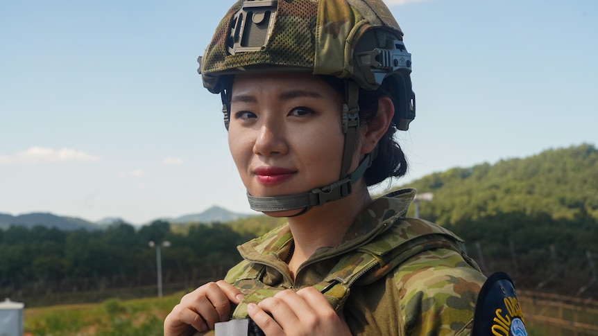 A close up of a woman wearing a helmet and army fatigues.