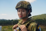 A close up of a woman wearing a helmet and army fatigues.
