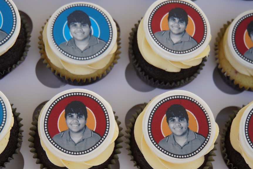 Four cupcakes with a black and white picture of an Indigenous boy on top