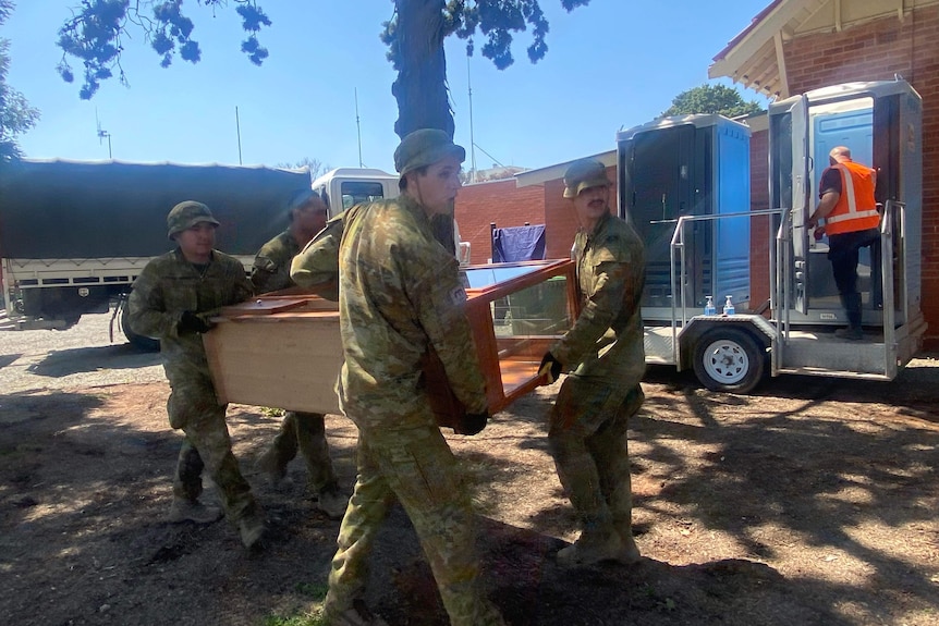 ADF personnel helping with recovery effort, with portable toilet in the background 