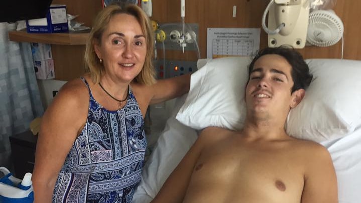 A man on a hospital bed with a woman standing next to him.