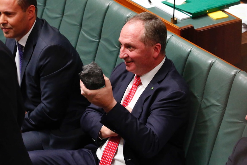 Barnaby Joyce holds a lump of coal while sitting on the frontbench in Parliament.