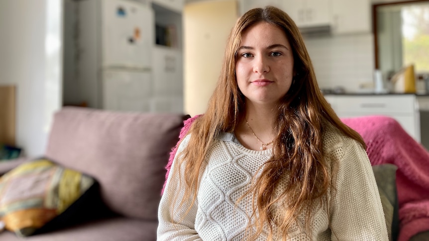 A young woman with long brown hair looks into the camera