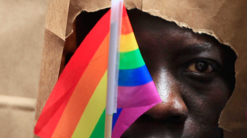 An asylum seeker from Uganda covers his face with a paper bag in order to protect his identity at a gay pride parade in Boston.