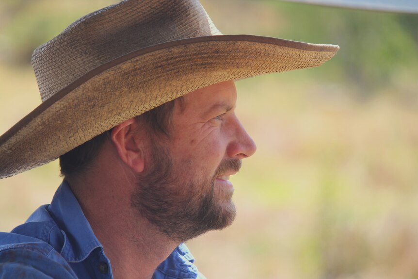 A farmer wearing a hat is pictured closeup from the side.