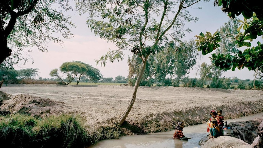 Women and children bathe in an open stream in Talib Lashari, Pakistan.
