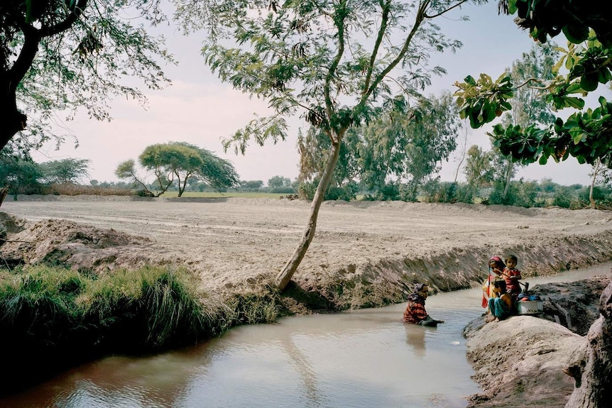 Women and children bathe in an open stream in Talib Lashari, Pakistan.