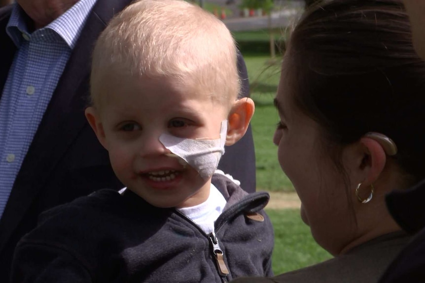 A boy with a tube taped to his face with a woman