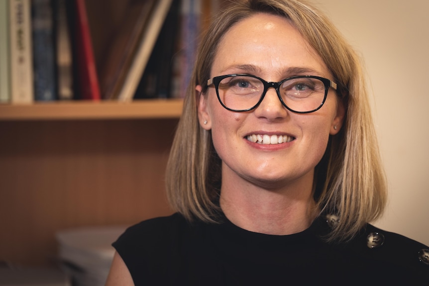 a woman wearing glasses smiles