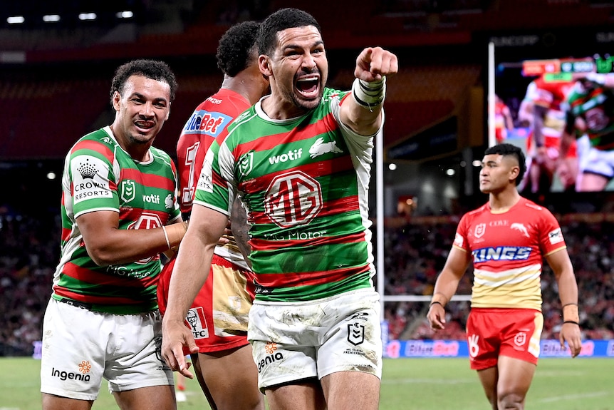 A South Sydney NRL player points a finger on his left hand as he celebrates a try against the Dolphins.
