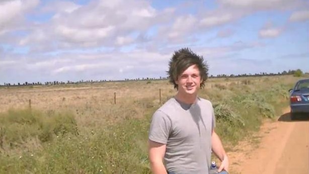 Teenage boy stands on country dirt road