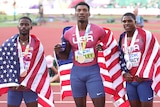 Three male American athletes stand alongside each other with the US flag over their shoulders.