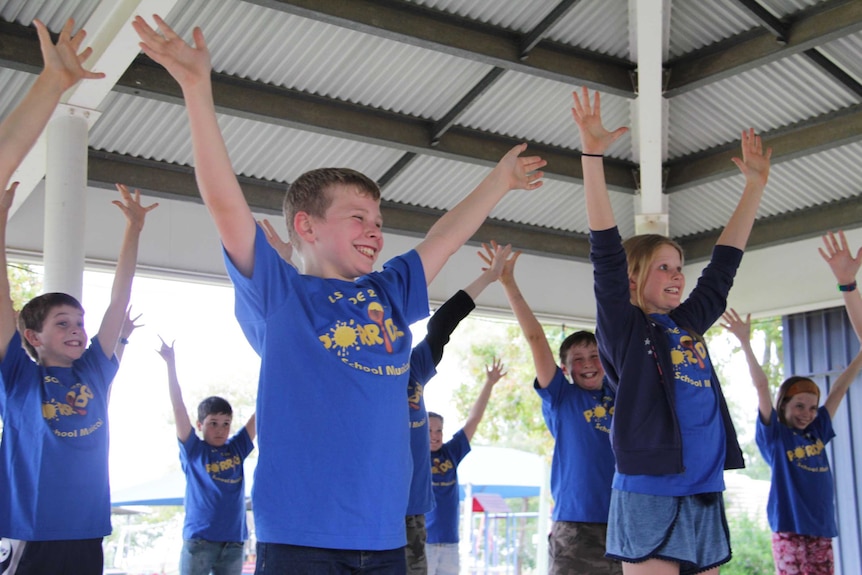 Children dancing in blue shirts.