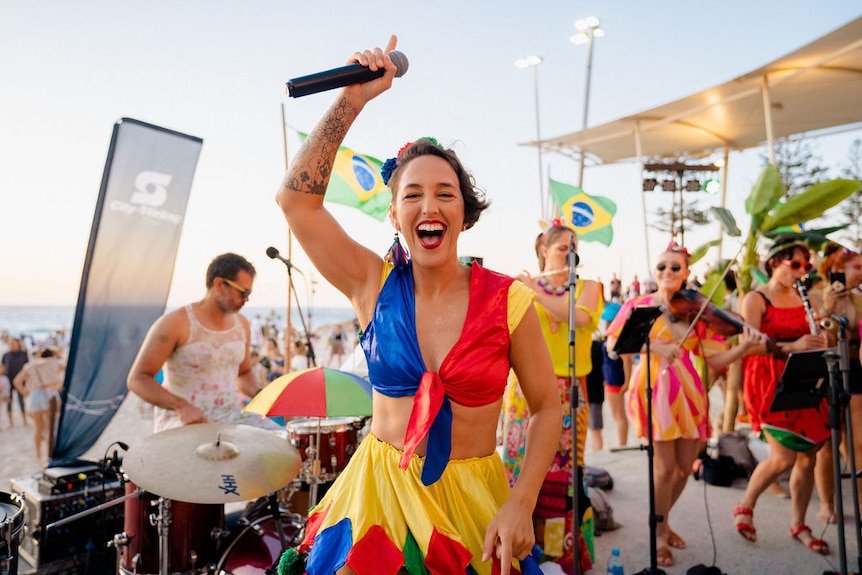 woman with microphone dancing in front of a band 