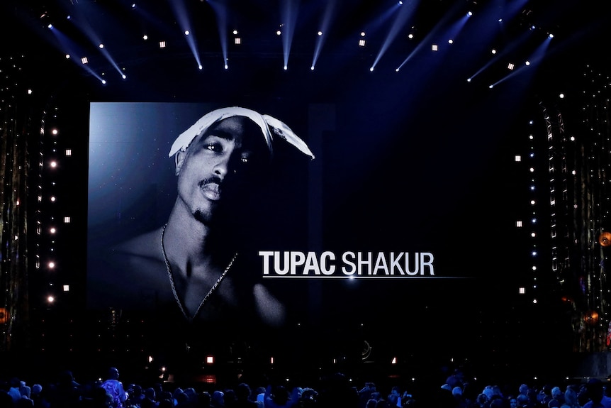 A image of rapper Tupac Shakur shown at a conert. 