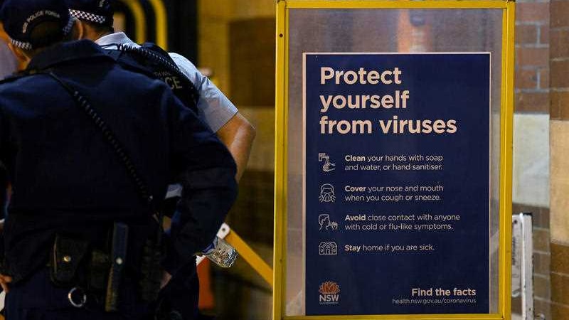 Police officers next to a coronavirus information sign.