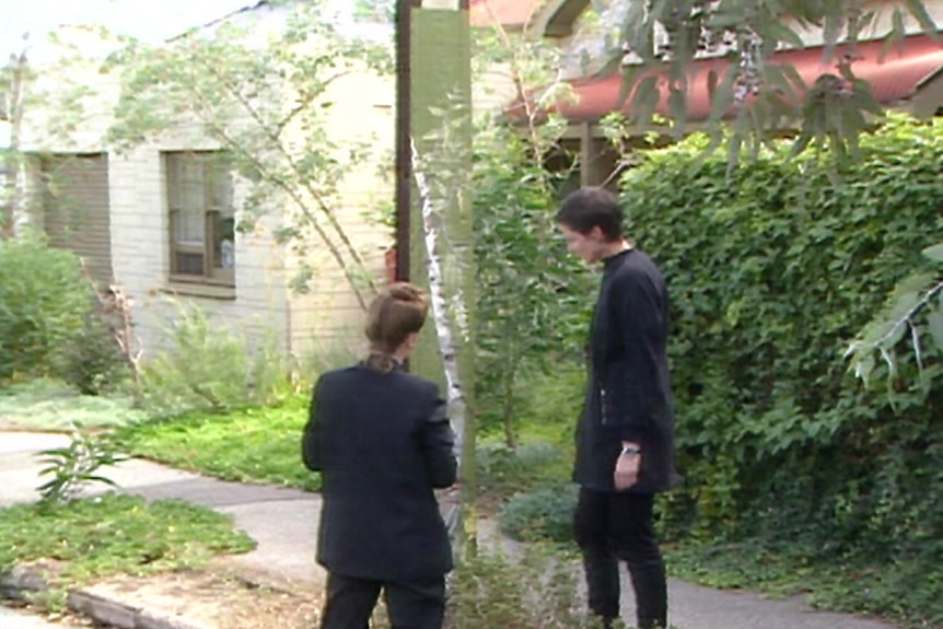 Two women stand next to a painted Stobie pole talking