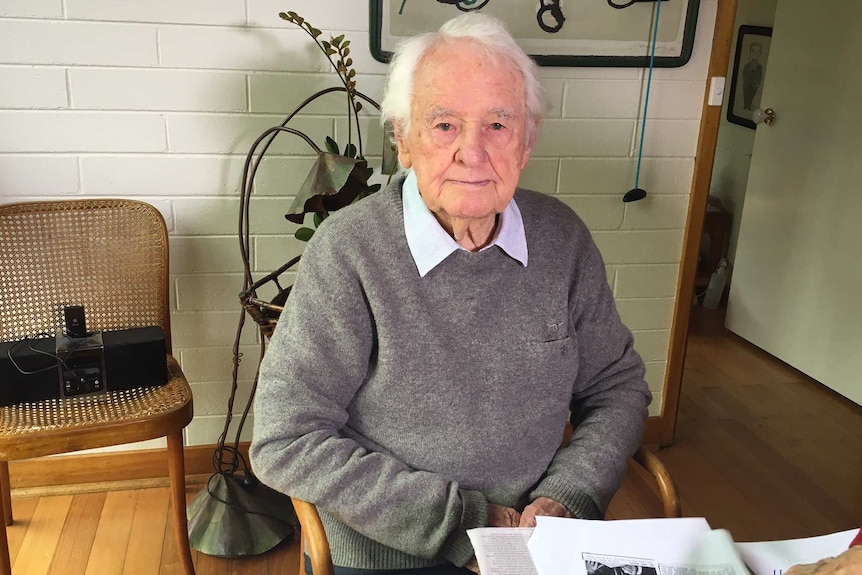 Dr Neil Davey sits at a table in him home.