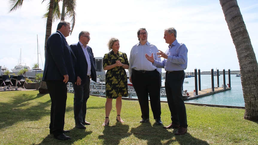 Four men and one woman stand together discussing a gas plan