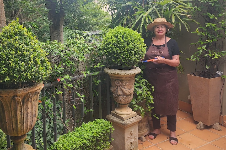 woman standing on a porch garden with cutters in her hand, standing