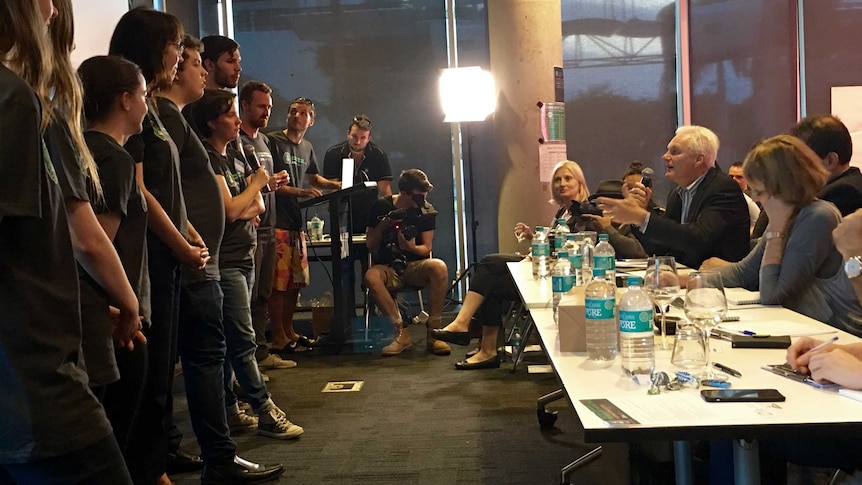 Winning team Shario stands with a microphone directly opposite a panel of judges during their pitch.