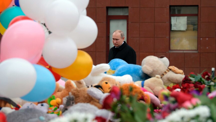 Vladimir Putin walks past a memorial for the victims of shopping centre fire in the Siberian city of Kemerovo.