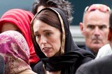 Jacinda Ardern, wearing a headscarf, walks to mourners