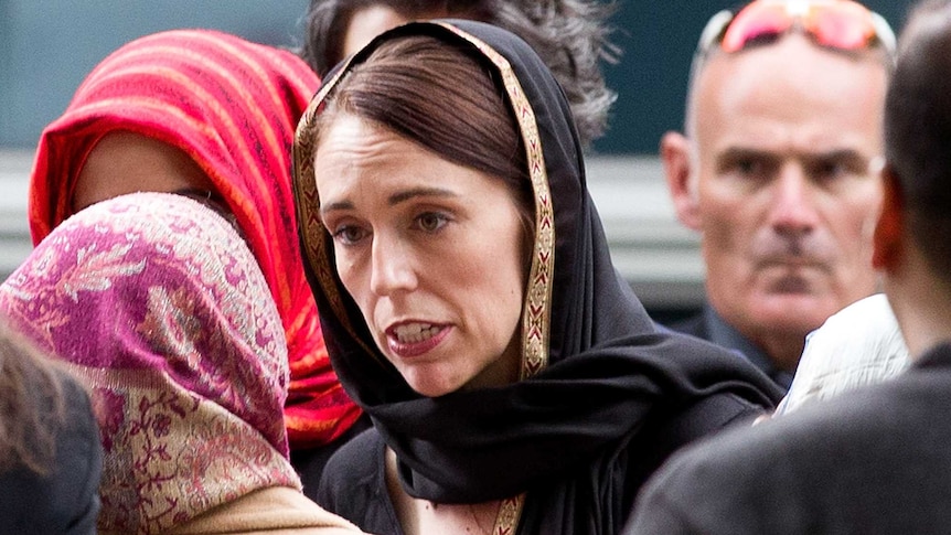 Jacinda Ardern, wearing a headscarf, walks to mourners
