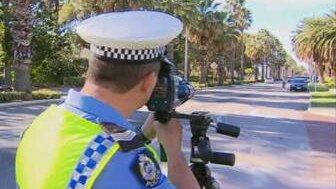 There are few cars on Riverside Drive as a police officer points a speed camera at traffic