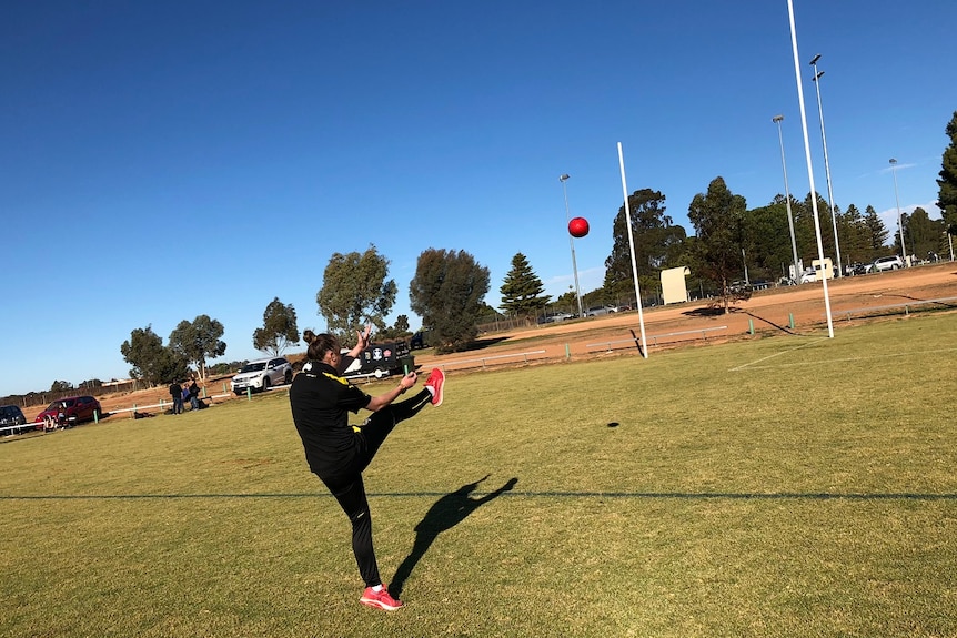 Female footballer kicks football at goal posts