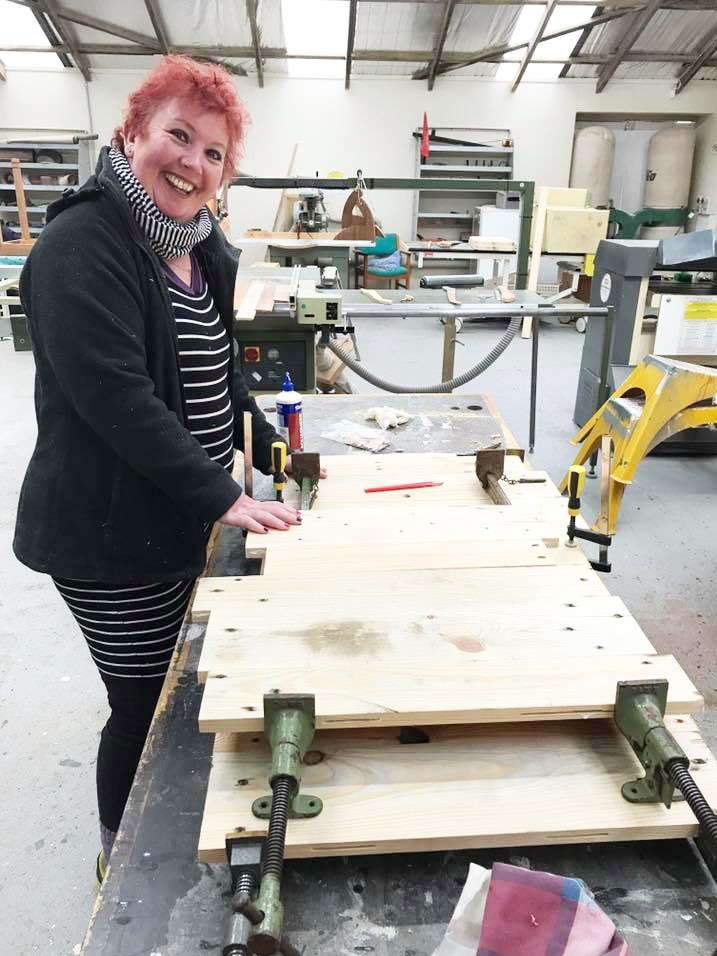 Sheree Whittington standing at a bench in the casket workshop.