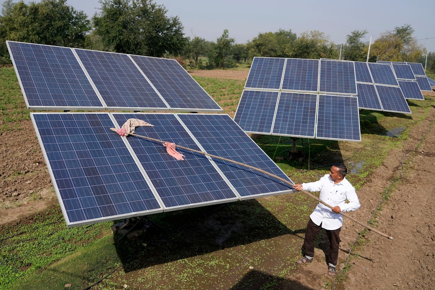 Farmer Pravinbhai Parmar cleans a solar panel installed at his farm.