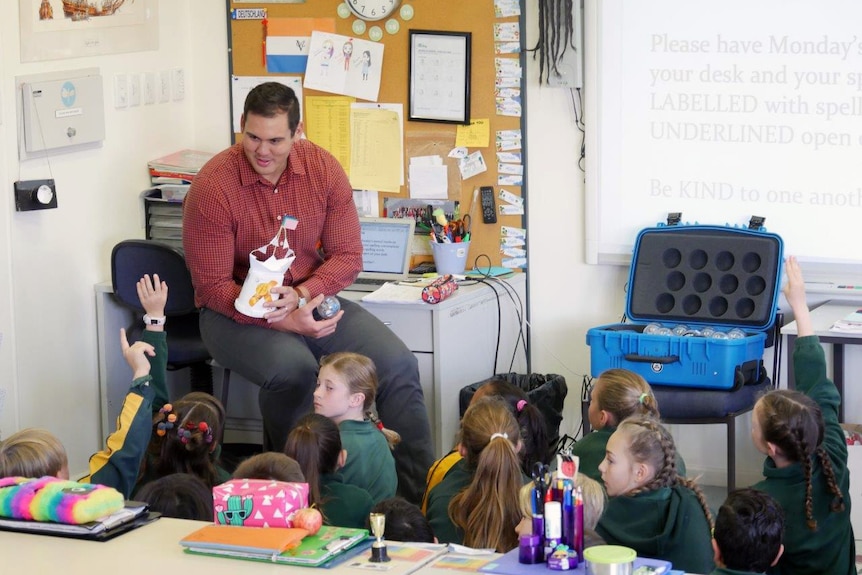 Karl Bodenstedt talks to students sitting on the classroom floor.