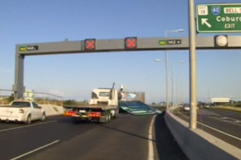 A screenshot of a freeway with vehicles parked behind a fallen sign