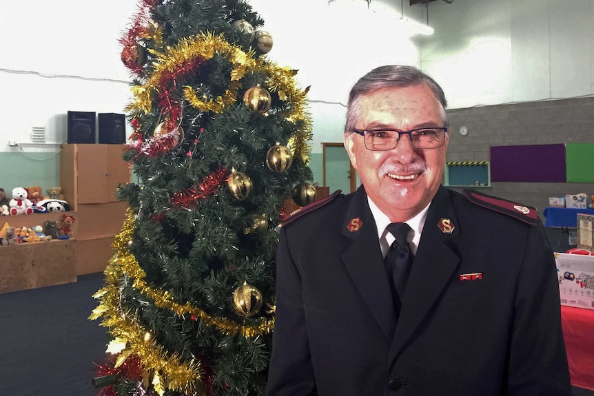 Salvation Army Tasmanian boss Major John Friend stands in front of a Christmas tree, December 2016.