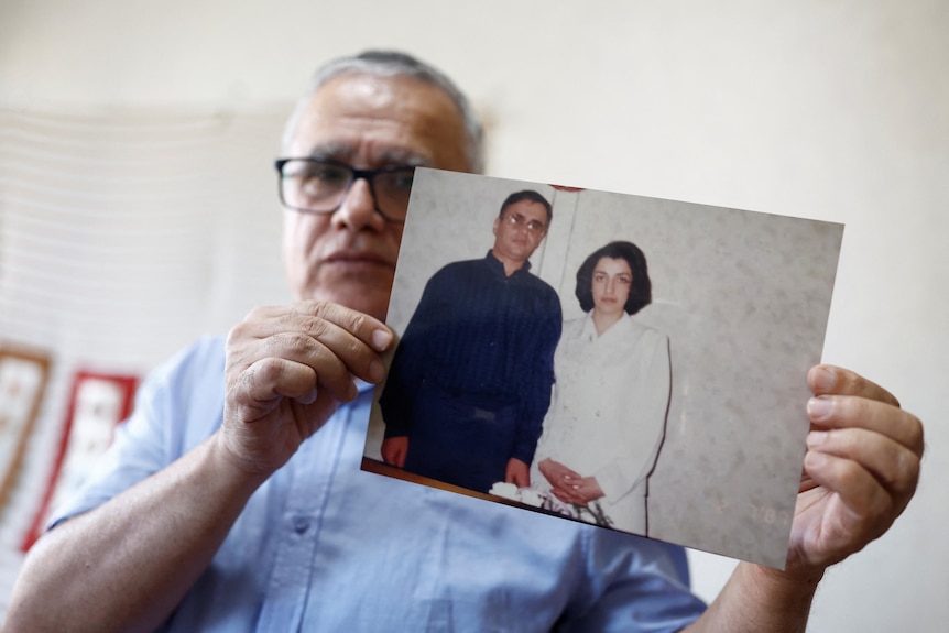 Taghi Ramahi holds up a photo of a younger version of himself and wife Narges Mohammadi