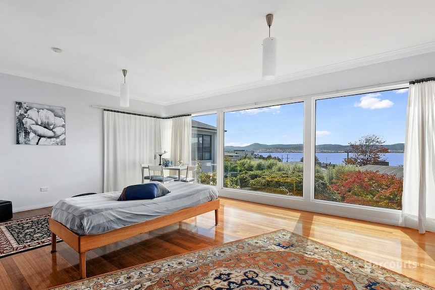 A scenic view of the coast from a light-filled living space with wooden floors.