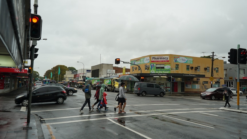 people cross a street at a four-way intersection on a rainy day