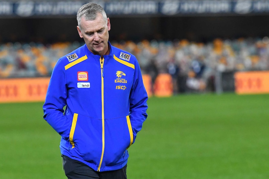 Adam Simpson walks across the field with his head down and hands in his pockets