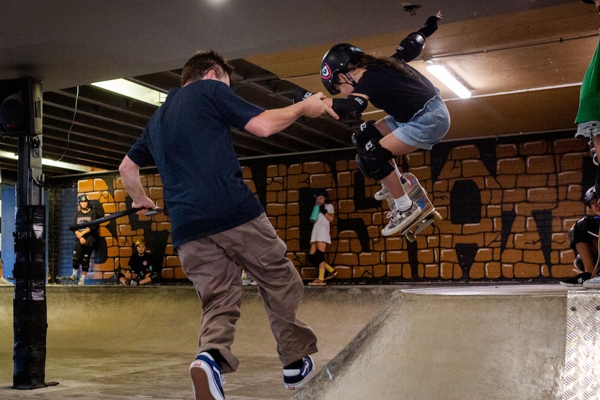 Alegra gets air as she rides up the side of the bowl. She holds Ando's hand for support.