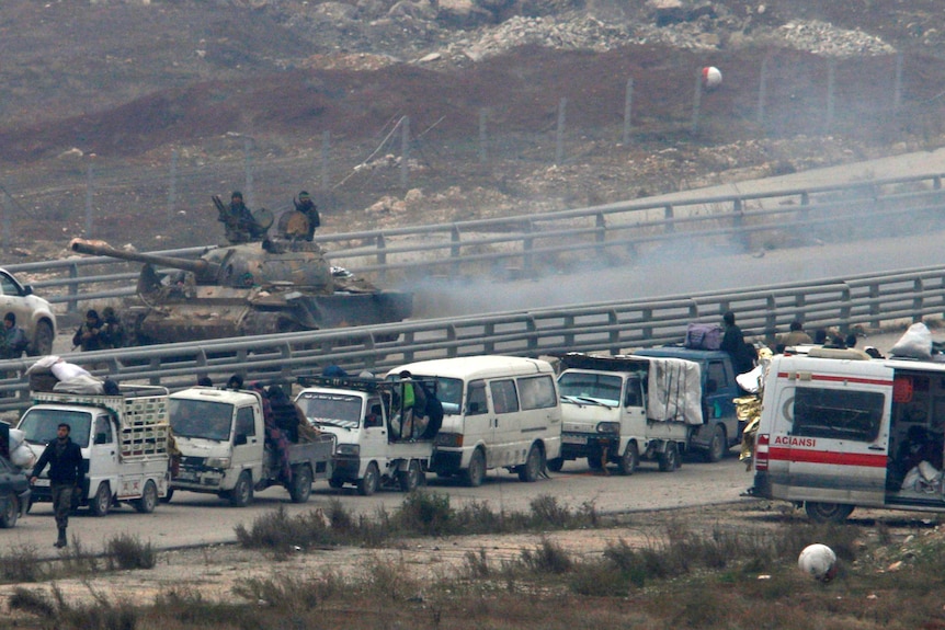 Forces loyal to Syria's President Bashar al-Assad sit on a tank as a convoy of buses turns back.