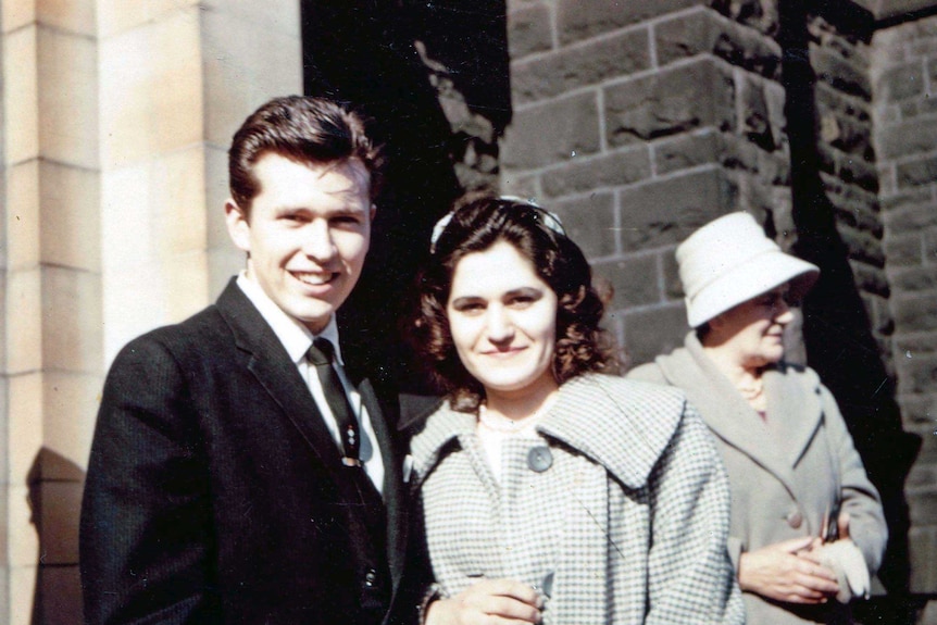 Maria James stands with her husband John outside a building.