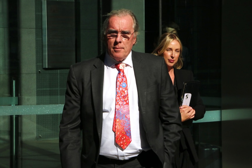 David Bennett leaves court wearing a dark suit and a colourful tie at the end of the directions hearing.