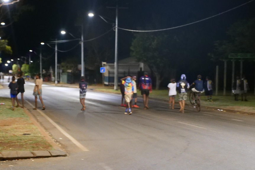 група деца се разхождат по крайградска улица през нощта
