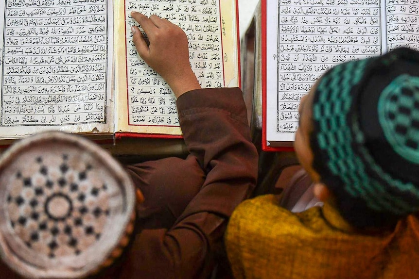 A birds eye view of two boys looking at the Koran