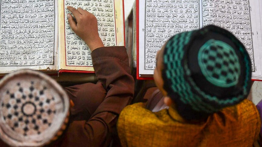 A birds eye view of two boys looking at the Koran